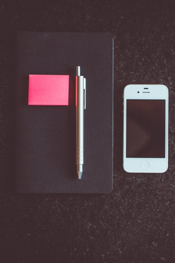 Returned work equipment after employment termination: smartphone, closed laptop, and pen.